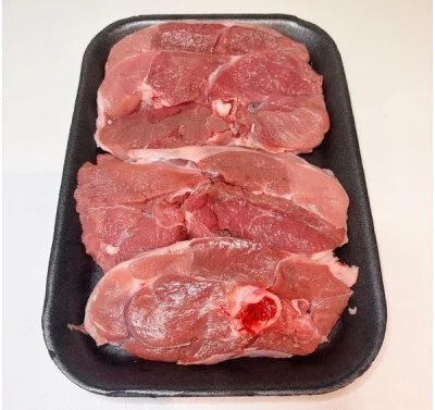 Bandeja con trozos de pierna de cordero cruda Aluju, de color rojo intenso y veteado natural, listos para cocinar.