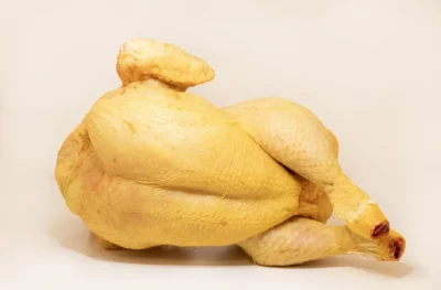 Un pollo entero dorado y crujiente servido en una bandeja con guarnición de patatas y verduras.
