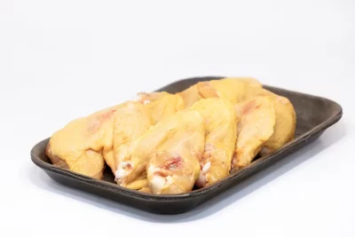 Alitas de pollo: el clásico irresistible Un plato de alitas de pollo doradas y crujientes, acompañadas de salsa barbacoa y apio fresco.