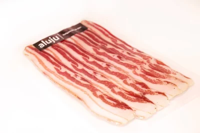 "Lonchas de tocino ibérico con vetas doradas y una textura untuosa."