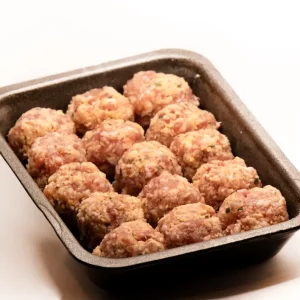 Albóndigas de cerdo caseras en salsa, servidas en cazuela de barro con pan rústico al lado.