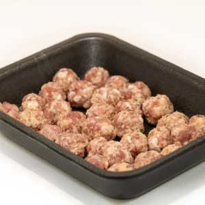 Mini albóndigas de cerdo doradas, servidas con salsa casera y acompañamiento de verduras.