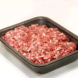 Carne picada de ternera: calidad y sabor en cada bocado Bandeja de carne picada de ternera fresca, con una textura uniforme y color rojo intenso, lista para cocinar.