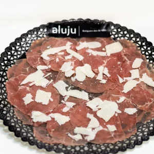 Carpaccio de ternera con finas lonchas de carne cruda, lascas de parmesano, rúcula fresca y aliño de aceite de oliva y limón.