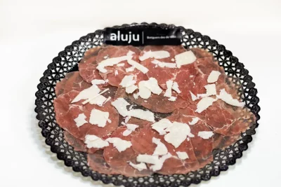Carpaccio de ternera con finas lonchas de carne cruda, lascas de parmesano, rúcula fresca y aliño de aceite de oliva y limón.