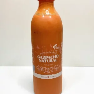 Botella de gazpacho natural con etiqueta ilustrada, sobre fondo blanco, destacando ingredientes frescos como tomate, pepino y pimiento.