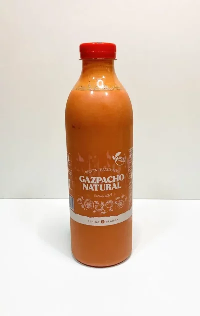 Botella de gazpacho natural con etiqueta ilustrada, sobre fondo blanco, destacando ingredientes frescos como tomate, pepino y pimiento.