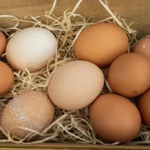 Huevos camperos frescos en cesta de mimbre, con cáscara marrón y fondo rústico de madera.