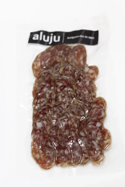 Longaniza de Caldes curada artesanalmente, con especias naturales, presentada en tabla rústica con pan y aceitunas.