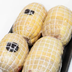 Muslos de pollo rellenos de jamón y queso, dorados y jugosos, servidos con salsa y guarnición.