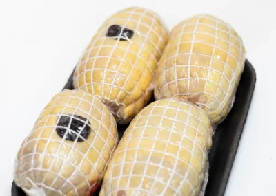 Muslos de pollo rellenos de jamón y queso, dorados y jugosos, servidos con salsa y guarnición.