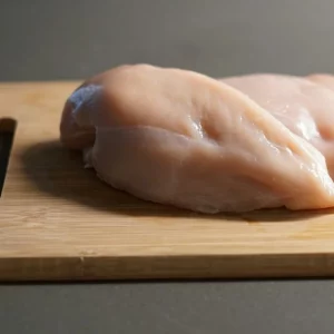 Pechugas de pollo fileteadas en tabla de cortar Pechugas de pollo crudas sobre tabla de cortar