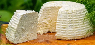 Queso fresco de cabra en porciones, con su textura cremosa y color blanco puro, listo para degustar.