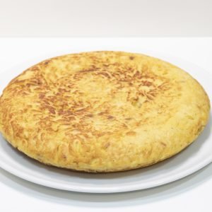 Tortilla de patatas sin cebolla, dorada por fuera y jugosa por dentro, servida en porciones sobre plato rústico.