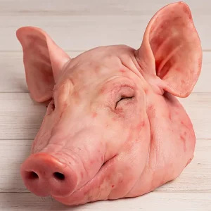 Una pieza de careta de cerdo cruda, con oreja y hocico visibles, lista para cocinar a la brasa, al horno o guisada.