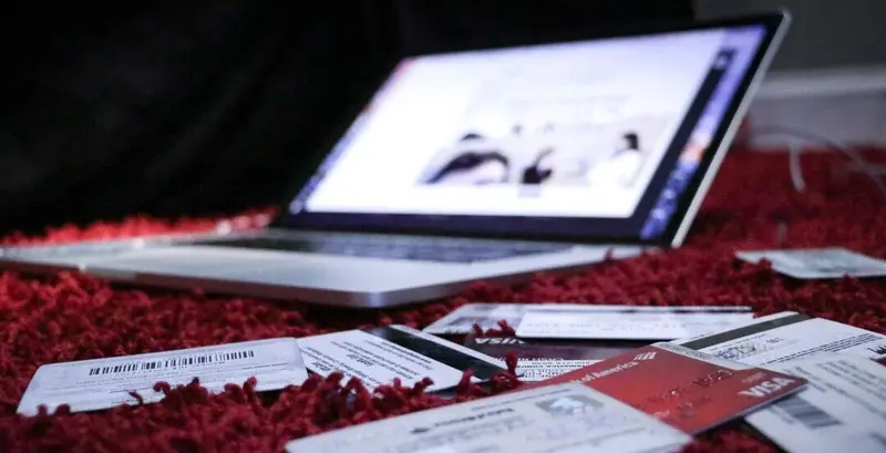 Imagen de presentación de cuenta Aluju, con ordenador portátil sobre alfombra roja y elementos cotidianos como tarjetas y documentos, que evocan actividad, autenticidad y conexión digital.