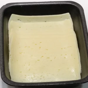 Lonchas de queso Havarti en envase transparente, de color amarillo pálido y textura suave con pequeños ojos.