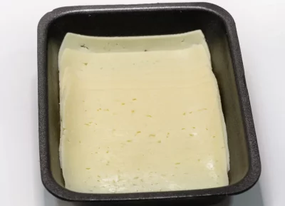 Queso Havarti en lonchas: suavidad danesa lista para disfrutar Lonchas de queso Havarti en envase transparente, de color amarillo pálido y textura suave con pequeños ojos.
