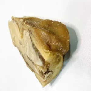Hueso de jamón curado con restos de carne, envase transparente, ideal para enriquecer platos tradicionales.