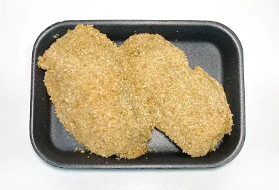 Dos libritos de pollo empanados, dorados y crujientes, presentados en bandeja negra, listos para freír o cocinar al horno.