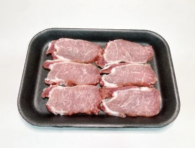 Bandeja con piezas de lomo ibérico crudo Aluju, de aspecto marmoleado y color rojizo, listas para cocinar.