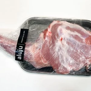Paletilla de cordero Aluju cruda, envasada en bandeja negra y envuelta en plástico transparente, lista para cocinar al horno o a la brasa.
