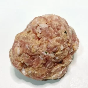Una pieza de pelota de carne cruda Aluju, con forma redondeada y textura casera, lista para cocinar en caldo o guiso.