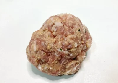 Pelota Aluju: el alma del cocido con sabor casero Una pieza de pelota de carne cruda Aluju, con forma redondeada y textura casera, lista para cocinar en caldo o guiso.