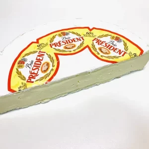 Cuña de queso Brie Président con corteza blanca y textura cremosa, presentada en envase con logotipo visible y 60 % de materia grasa.
