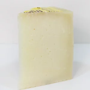 Cuña de queso semicurado Montescusa con corte amarillo pálido y textura compacta, sobre tabla de madera.