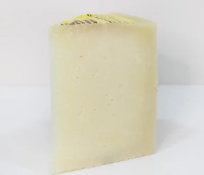 Cuña de queso semicurado Montescusa con corte amarillo pálido y textura compacta, sobre tabla de madera.