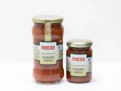 Tomate Frito Marzo: sabor casero con sello riojano Dos frascos de Tomate Frito Marzo con tapa dorada y etiqueta roja, uno grande y otro pequeño, sobre fondo blanco, que representan calidad y tradición riojana.